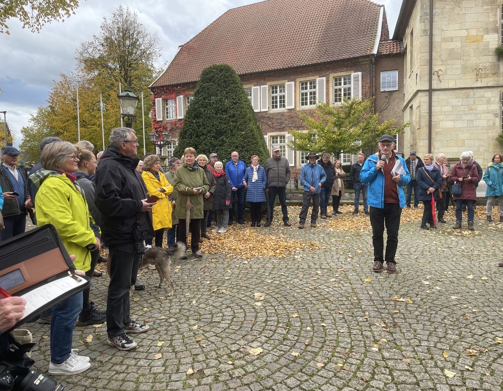 Dr. Mathias Austermann mit Mikrofon spricht, um ihn herum stehen Menschen und hören zu.
