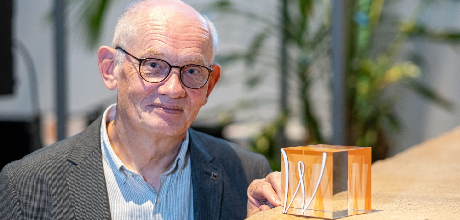 Mathias Austermann, Mann mit grauem Haar und Brille, steht lächelnd neben dem Karl-Zuhorn-Preis.
